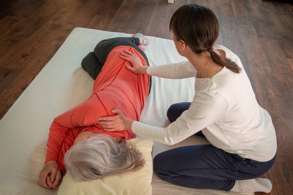 Liz giving Shiatsu, receiver lying on their side on the futon seen from above their head