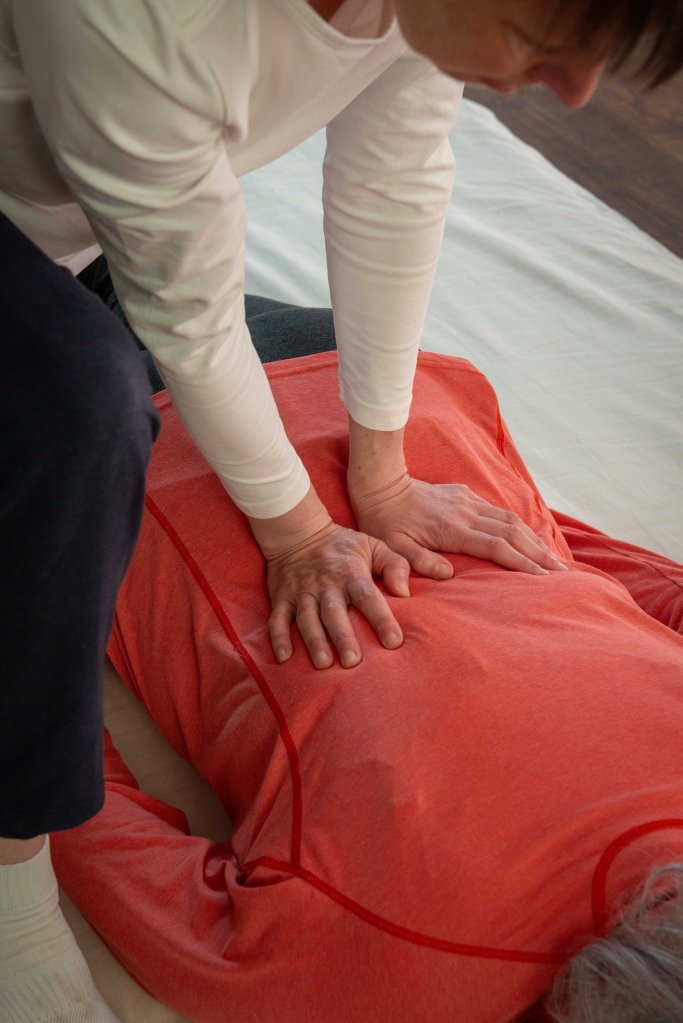 Close up of Liz's hands applying Shiatsu touch to the receiver back