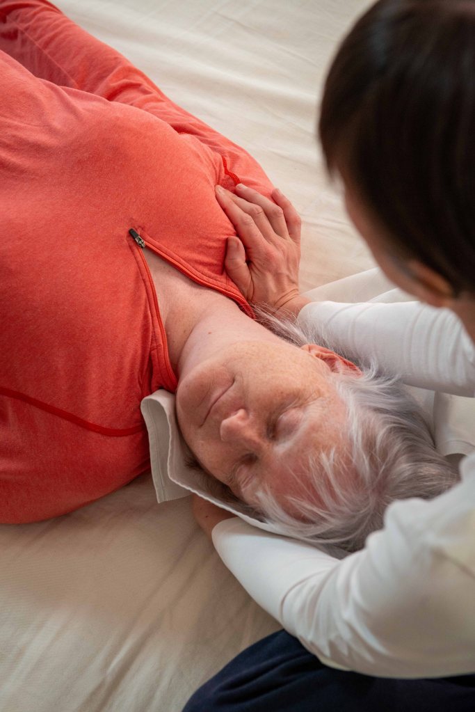 Close up of receiver, Liz applying Shiatsu touch to their upper body